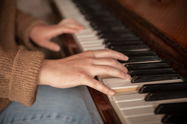 Primo piano delle mani di un pianista sui tasti del pianoforte, mani femminili che suonano il pianoforte.