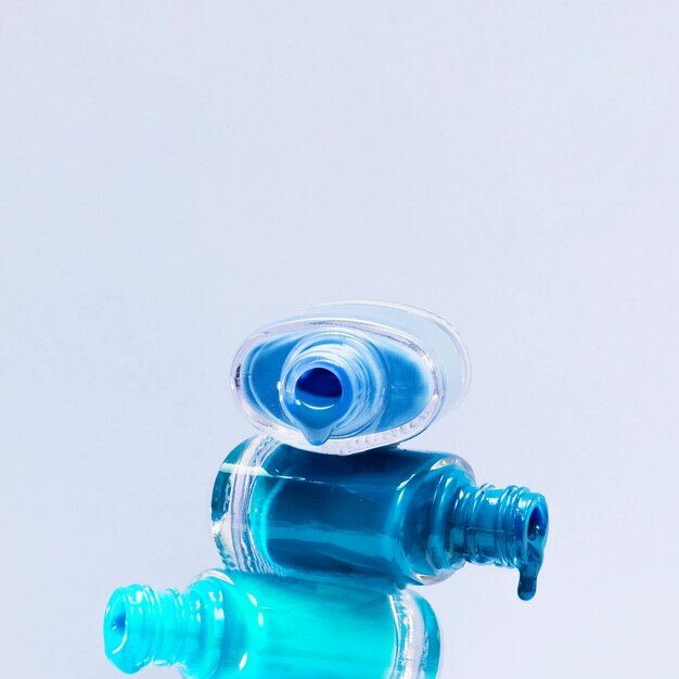 Primo piano dello smalto di tonalità blu con la bottiglia aperta impilata