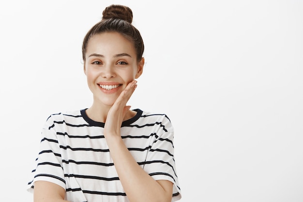 Primo piano di bella donna sorridente che tocca la guancia pulita della pelle perfetta, il concetto di bellezza e cura della pelle