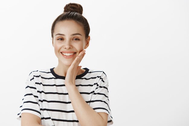 Primo piano di bella donna sorridente che tocca la guancia pulita della pelle perfetta, il concetto di bellezza e cura della pelle