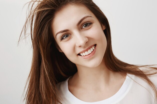 Primo piano di bella giovane donna che sembra felice, sorridente con i denti bianchi
