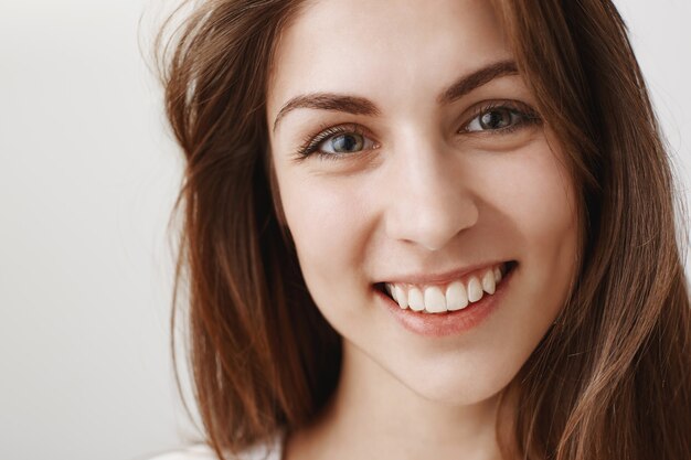 Primo piano di bella giovane donna che sembra felice, sorridente con i denti bianchi