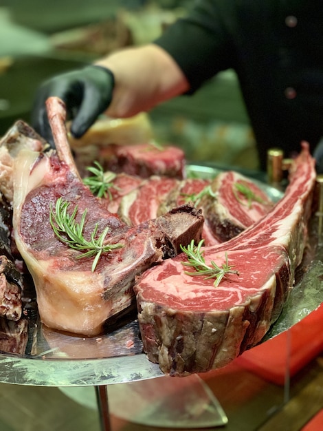 Primo piano di carne rossa cotta su una piastra metallica con lo chef in background