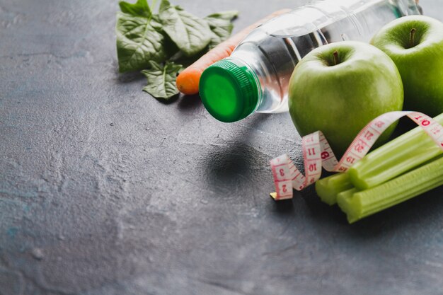 Primo piano di cibo sano con la bottiglia di acqua e misura di nastro