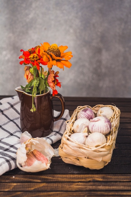 Primo piano di cipolle; spicchi d&#39;aglio; fiore e panno sul ripiano del tavolo in legno