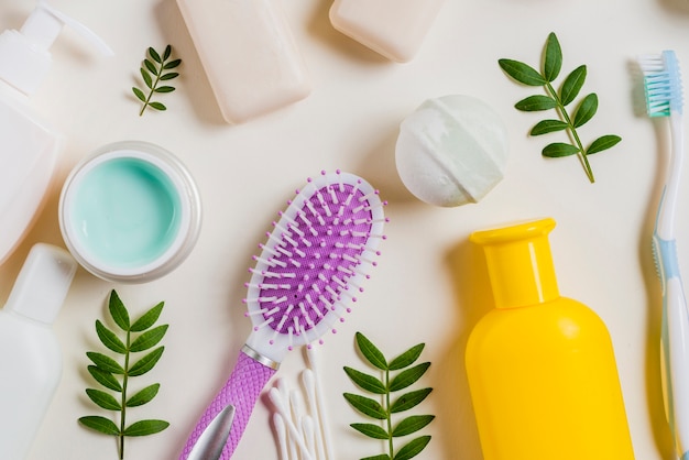 Primo piano di crema; spazzola per capelli; sapone; bomba da bagno; spazzolino da denti su sfondo bianco