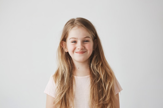 Primo piano di dolce bambina con i capelli lunghi chiari e le guance rosse con espressione volubile, andando a fare qualcosa di brutto.