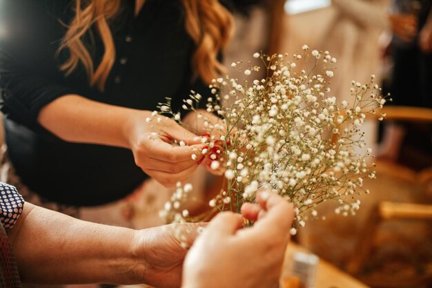 Primo piano di due donne irriconoscibili che fanno composizioni floreali prima della cerimonia di matrimonio