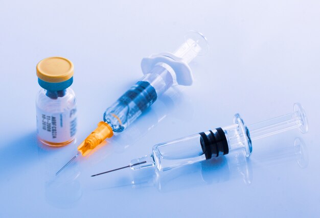Primo piano di due siringhe accanto a una fiala di vaccino contro l'influenza, COVID-19, morbillo o altre malattie
