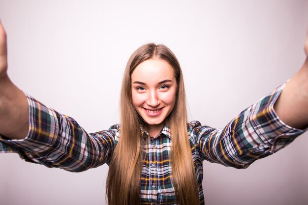 Primo piano di giovane bella donna che cattura selfie. Muro bianco isolato