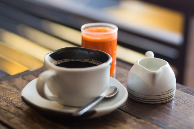 Primo piano di immagini di caffè mattutino e succo di carota sano, caffè biologico sano, piatti alla moda fatti a mano.