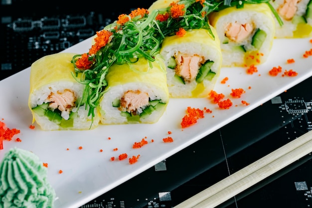 Primo piano di involtini di sushi con salmone fritto e cetriolo condita con alghe e tobiko rosso