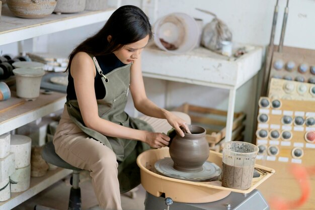 Primo piano di mani femminili che lavorano su vasai donna scultura femminile donna modellatura stampo vaso piccolo ciotola argilla sul tornio del vasaio a casa studio officina arte e creazione hobby concetto