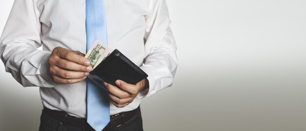 Primo piano di mani maschili che tengono un portafoglio in pelle aperto con denaro - concetto di successo finanziario