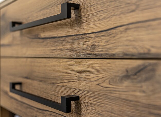 Primo piano di mobili moderni in legno scuro con maniglie nere.