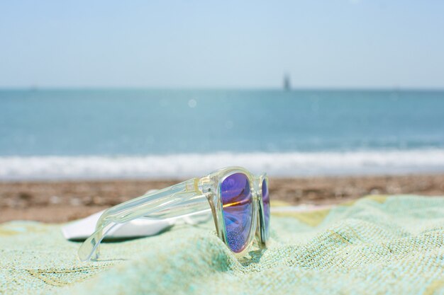 Primo piano di occhiali da sole funky sull'asciugamano da spiaggia su una spiaggia di sabbia