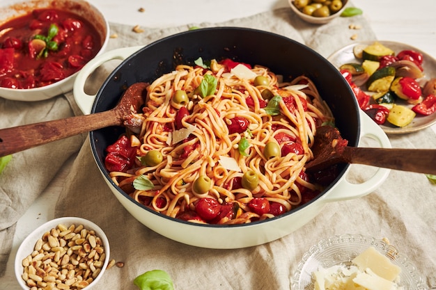 Primo piano di pasta con verdure e ingredienti su un tavolo bianco