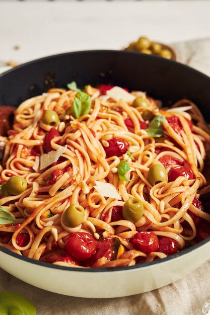 Primo piano di pasta con verdure e ingredienti su un tavolo bianco