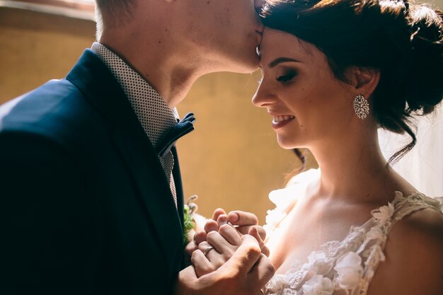 Primo piano di sposo baci la fronte della sposa