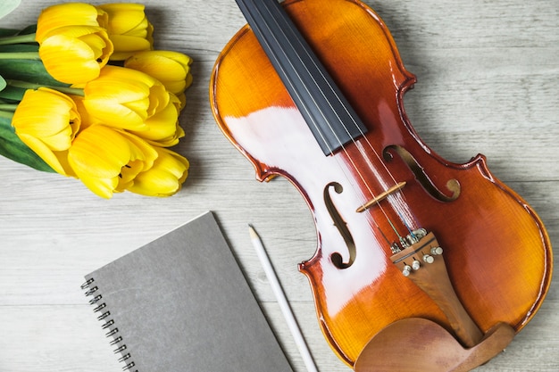 Primo piano di tulipani; diario; matita e violino su fondo in legno