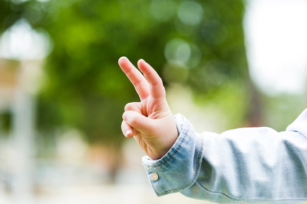 Primo piano di un bambino che gesturing il segno di pace