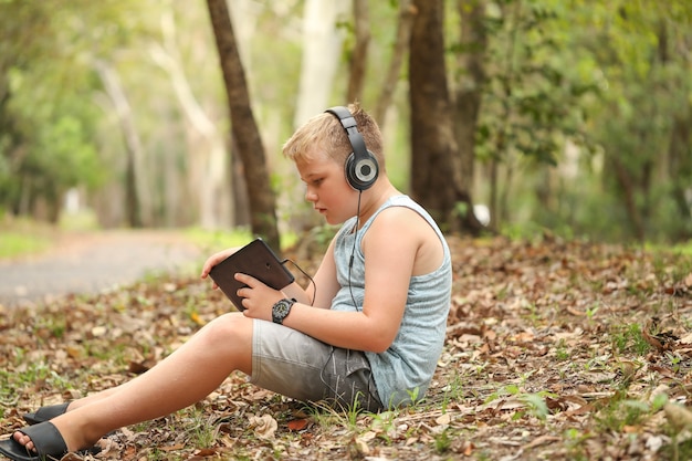 Primo piano di un bambino che usa un tablet e indossa le cuffie in natura