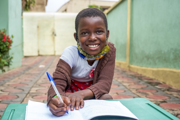 Primo piano di un bambino maschio nero che scrive su un taccuino