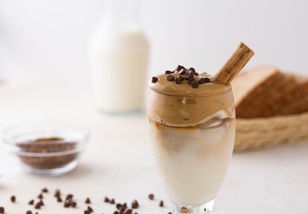 Primo piano di un bicchiere di caffè Dalgona con gocce di cioccolato su di esso con uno sfondo sfocato