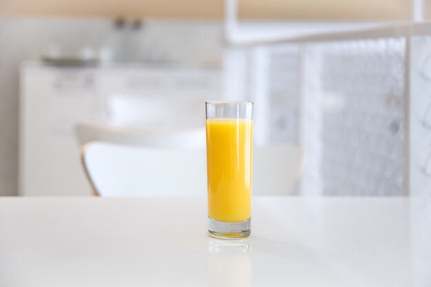 Primo piano di un bicchiere di succo d'arancia su uno sfondo chiaro sfocato di un interno di un caffè.