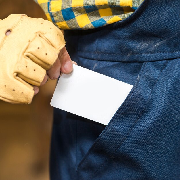 Primo piano di un carpentiere maschio che rimuove la carta in bianco bianca dalla sua tasca