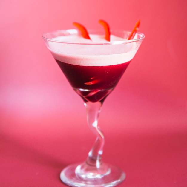 Primo piano di un cocktail fresco nel bicchiere da martini su sfondo rosa