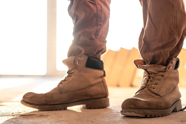 Primo piano di un costruttore in abiti da lavoro e stivali, primo piano, parte del corpo.