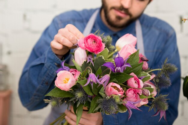 Primo piano di un fiorista maschio che organizza i fiori nel mazzo