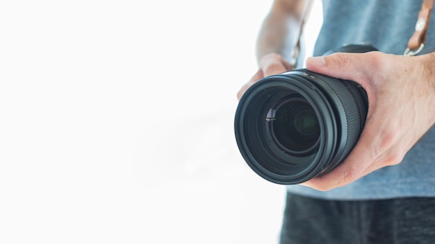 Primo piano di un fotografo che tiene la macchina fotografica del dslr su fondo bianco