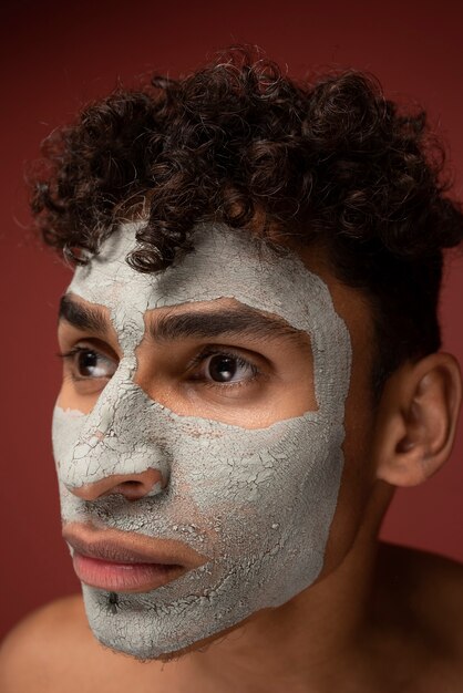 Primo piano di un giovane con una maschera facciale di bellezza addosso