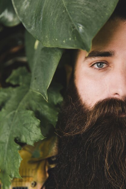 Primo piano di un giovane uomo con la barba lunga guardando fotocamera