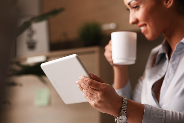 Primo piano di un imprenditore felice che si gode una pausa caffè mentre naviga in Internet sul touchpad