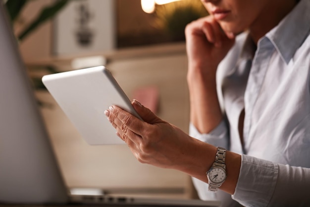 Primo piano di un'imprenditrice che legge rapporti aziendali su tablet digitale in ufficio