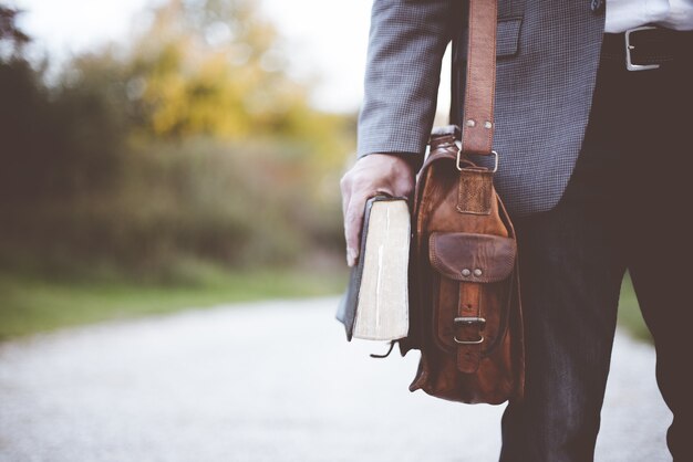 Primo piano di un maschio che indossa una borsa e nasconde la bibbia