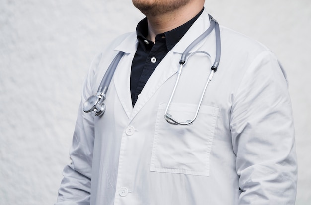 Primo piano di un medico maschio con lo stetoscopio intorno al suo collo contro il contesto bianco