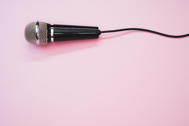 Primo piano di un microfono con un filo isolato su uno sfondo rosa con un'ombra