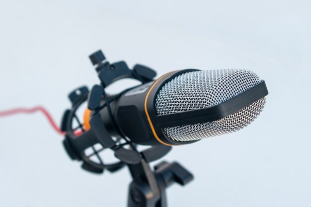 Primo piano di un microfono nero e grigio su una superficie e uno sfondo bianchi