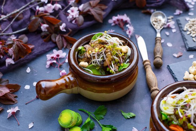 Primo piano di un pasto vegano con funghi, cipolle, carote e porri