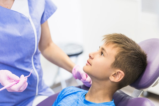 Primo piano di un paziente del bambino che si appoggia sulla sedia dentaria in clinica