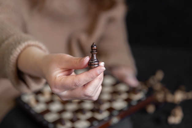 Primo piano di un pezzo degli scacchi in mani femminili sfondo sfocato