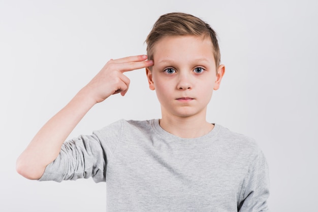 Primo piano di un ragazzo che fa il gesto pistola o pistola su sfondo grigio