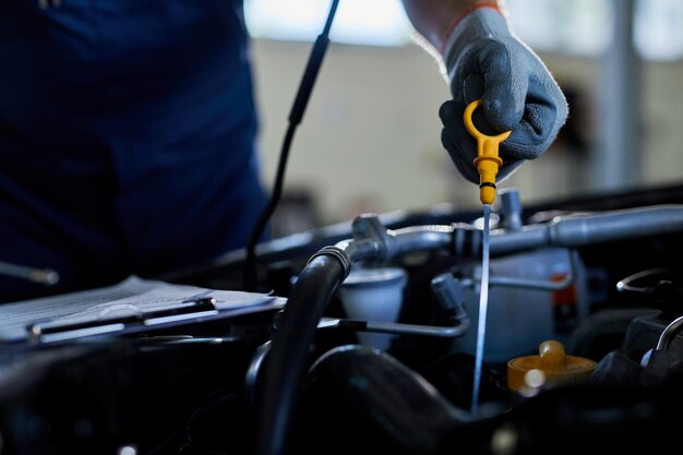 Primo piano di un riparatore automatico che controlla l'olio per auto in un'officina