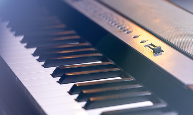Primo piano di un sintetizzatore o di un tasto di pianoforte in una splendida illuminazione scenica.
