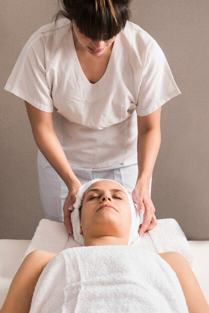 Primo piano di un terapista femminile avvolgendo asciugamano sulla testa della donna
