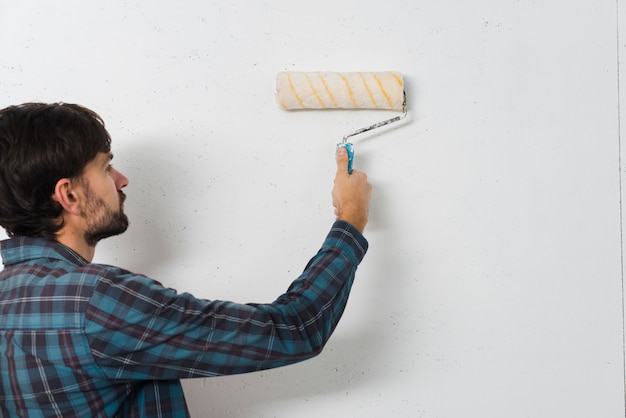 Primo piano di un uomo che dipinge il muro con rullo di vernice